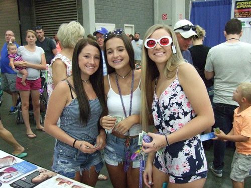 Three girls posing for a picture at an event.