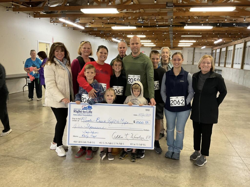 A group of people standing around a large check.