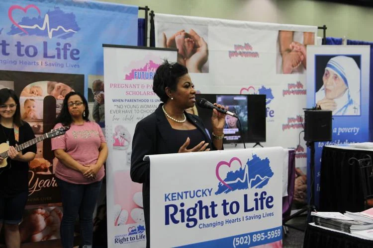 A woman standing at the podium speaking to people.