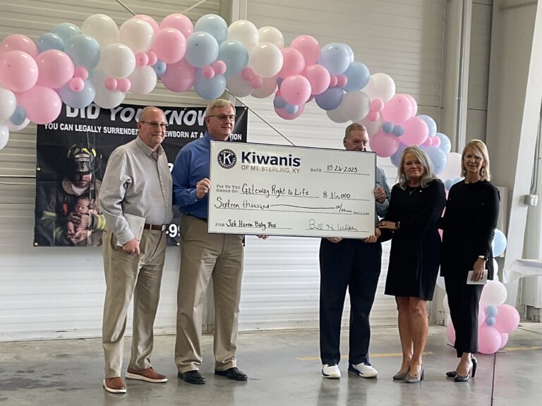 A group of people holding a check in front of balloons.