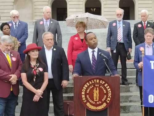 A man standing at the podium with people behind him.