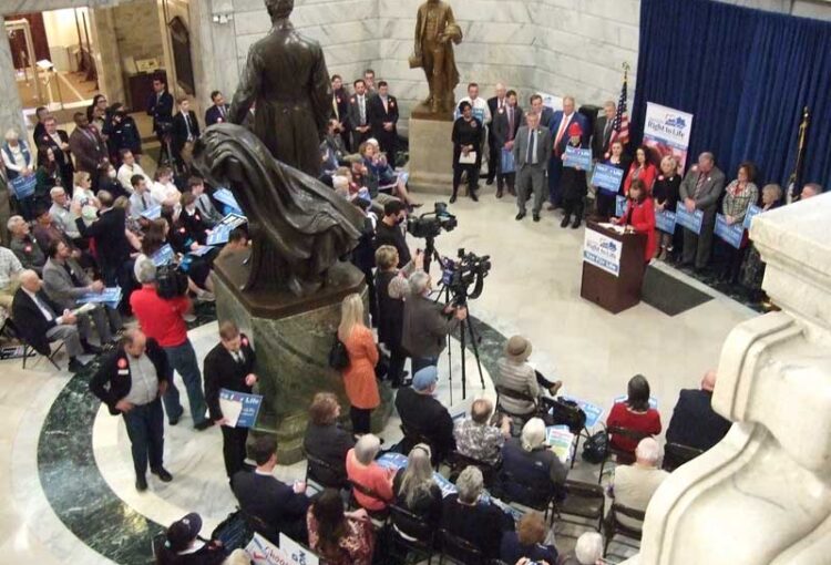 A crowd of people gathered in the lobby of a building.