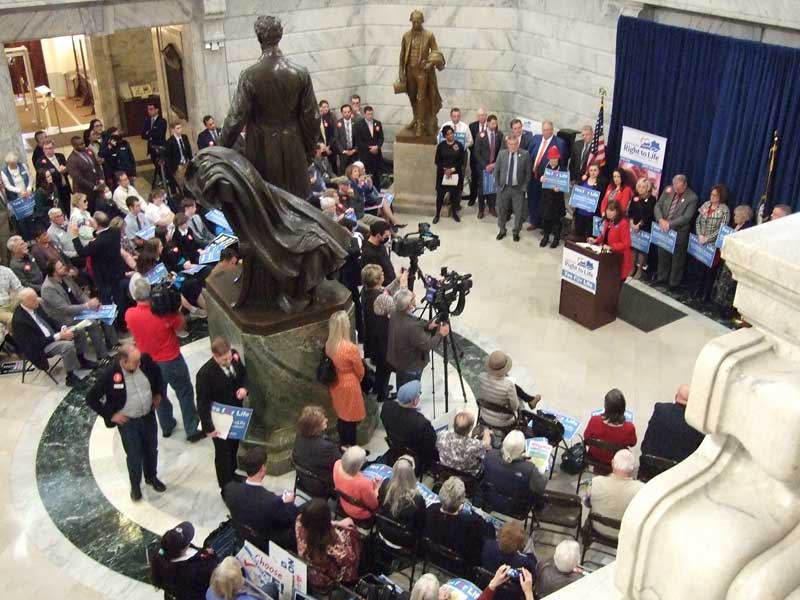 A crowd of people gathered in the lobby of a building.