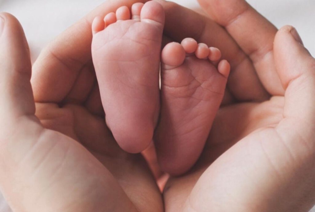 A pair of hands holding a baby's feet.